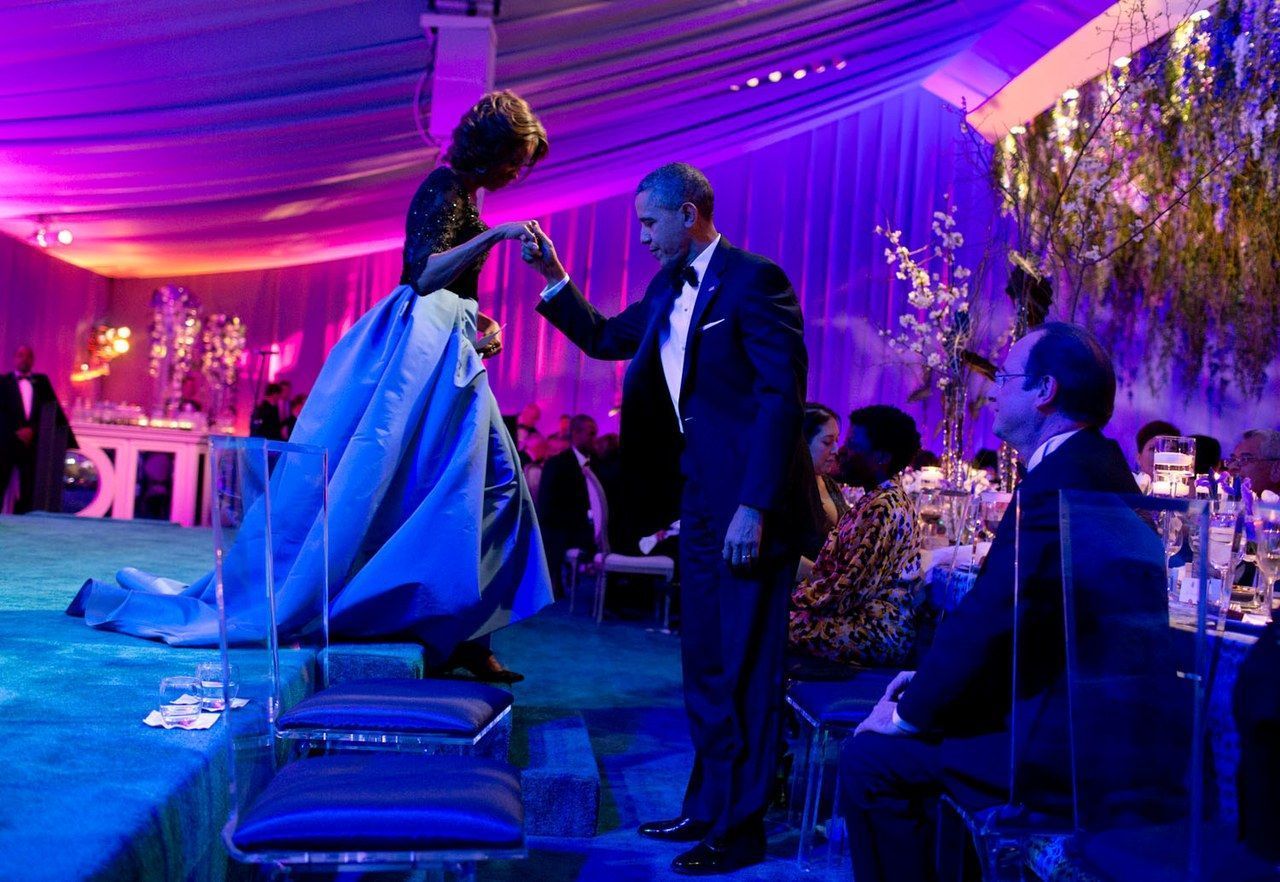 باراك helps Michelle off the stage after she thanked the White House chefs during the State Dinner for President François Hollande of France on the South Lawn of the White House in February 2014.