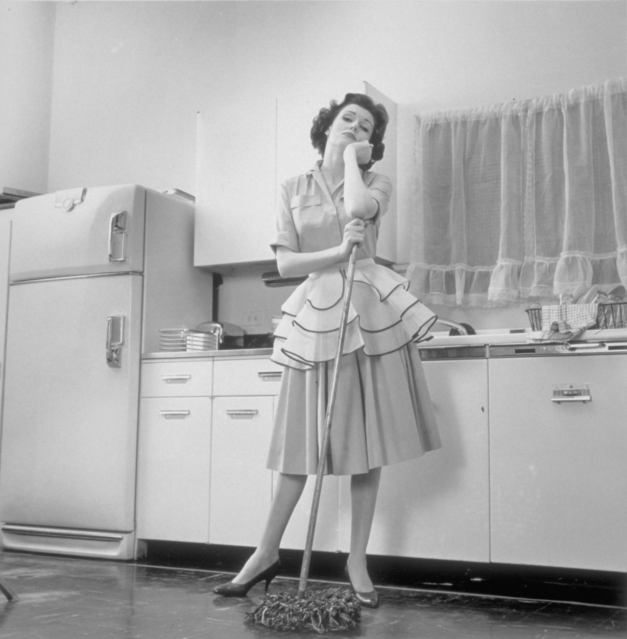 حسنا dressed woman in the kitchen leaning on a mop, New York, New York, December 2, 1962. (Photo by Camerique/Getty Images)