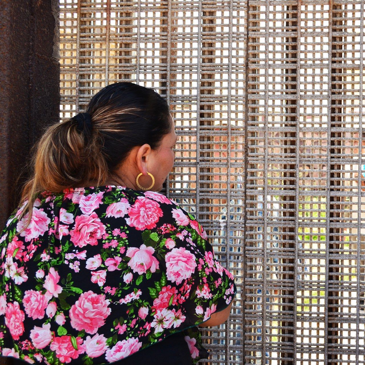 ا woman talks to her relatives across the fence separating